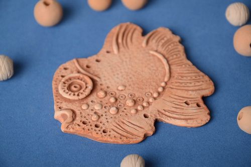 Homemade flat pendant molded of pottery clay in the shape of decorative fish - MADEheart.com