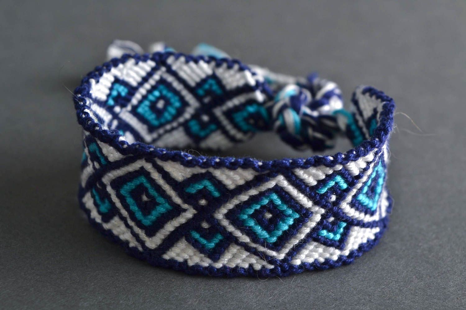 Handmade macrame bracelet woven of white and blue embroidery floss with ornament photo 1