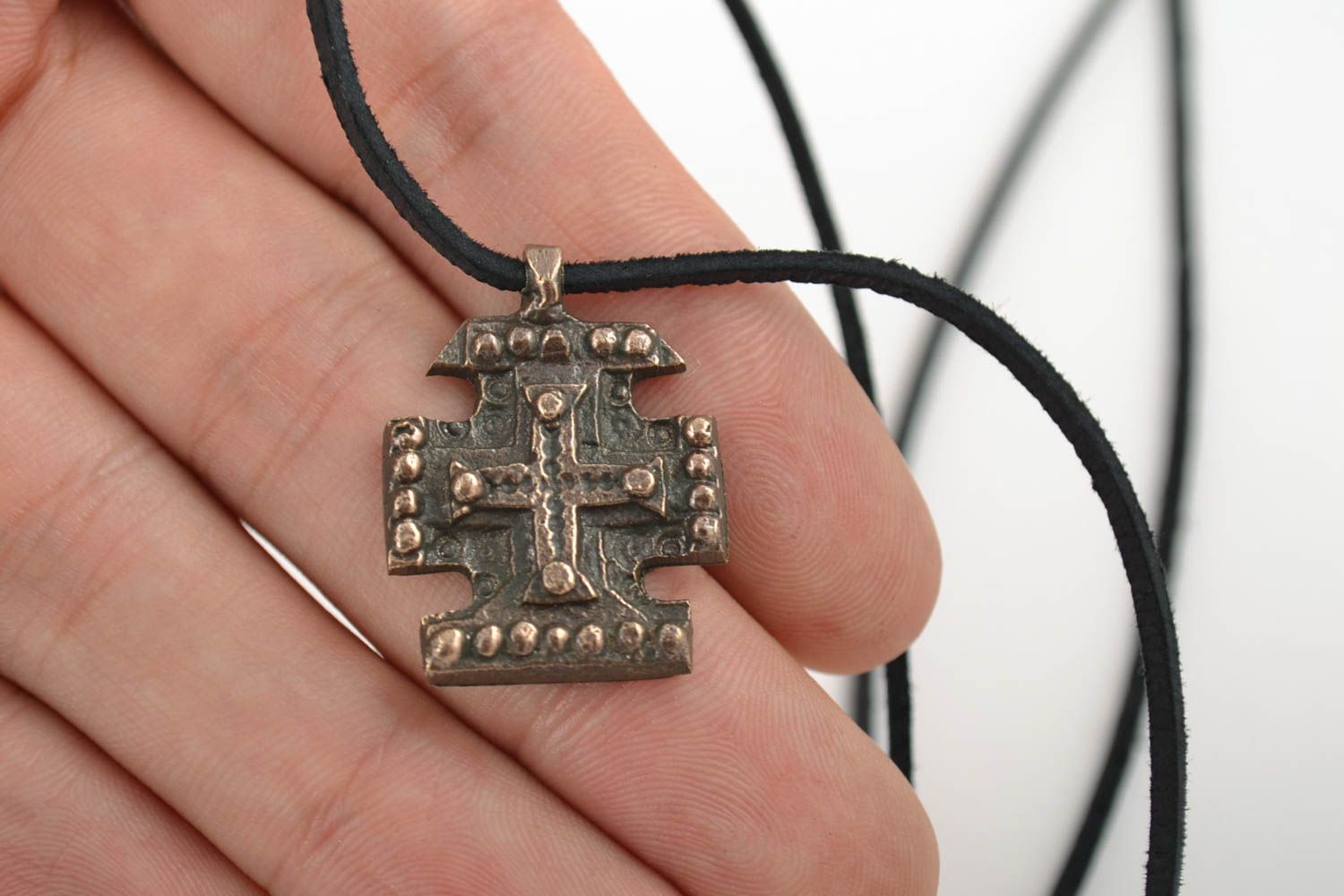 Pequeña cruz de bronce para el cuello hecha a mano en cordón foto 2