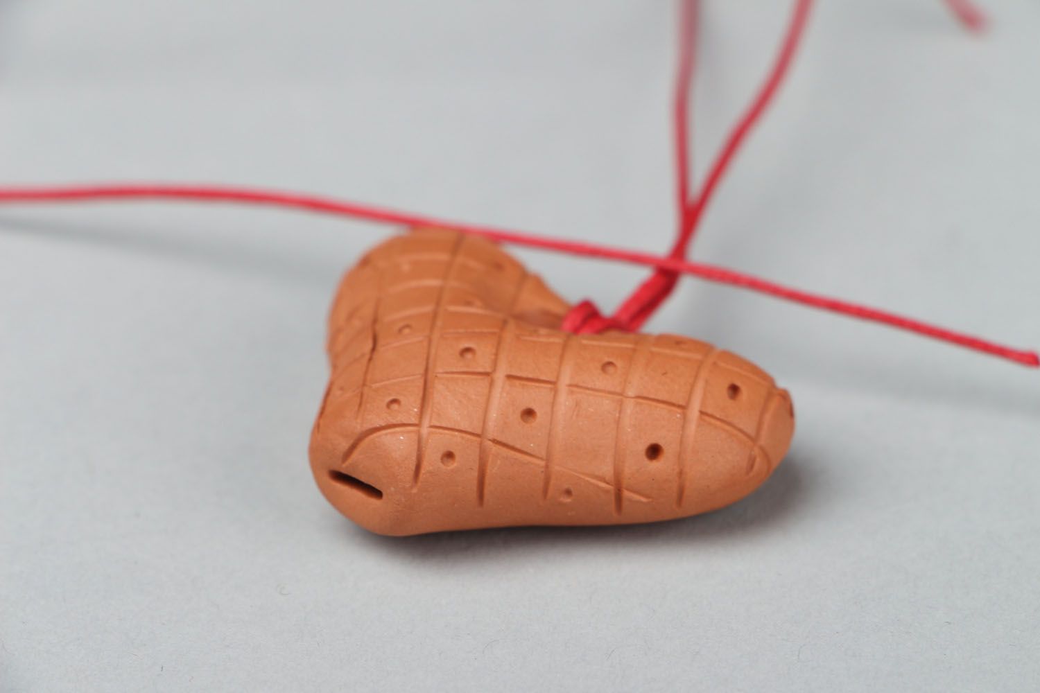Clay penny whistle with a red cord photo 2
