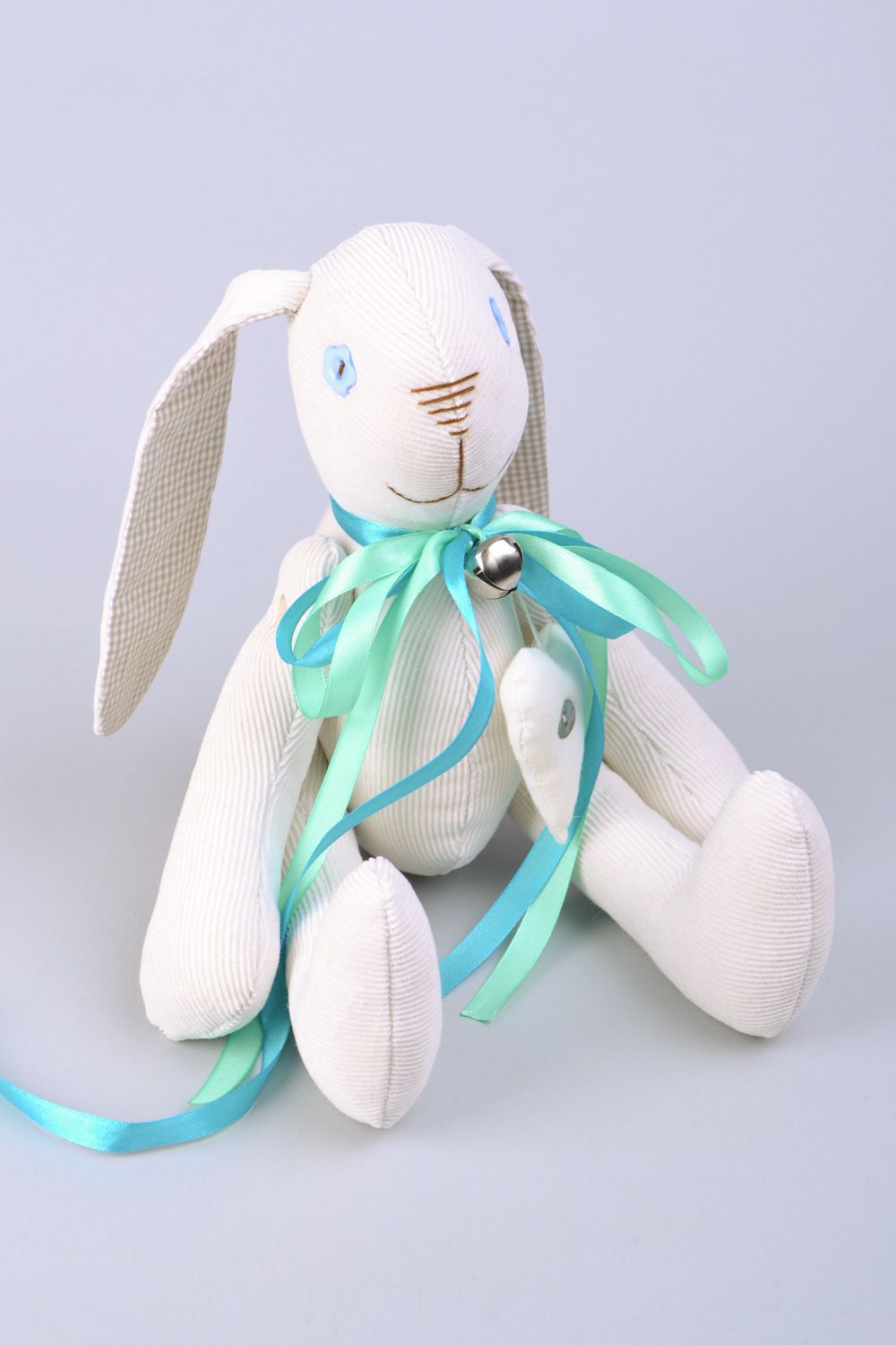 Handmade designer soft toy rabbit sewn of fabric of white color with blue bow photo 1