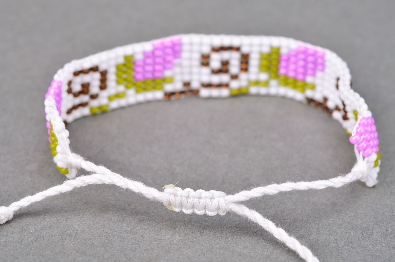 Stylish handmade women's wrist bracelet woven of beads and threads of light color with flower pattern photo 5