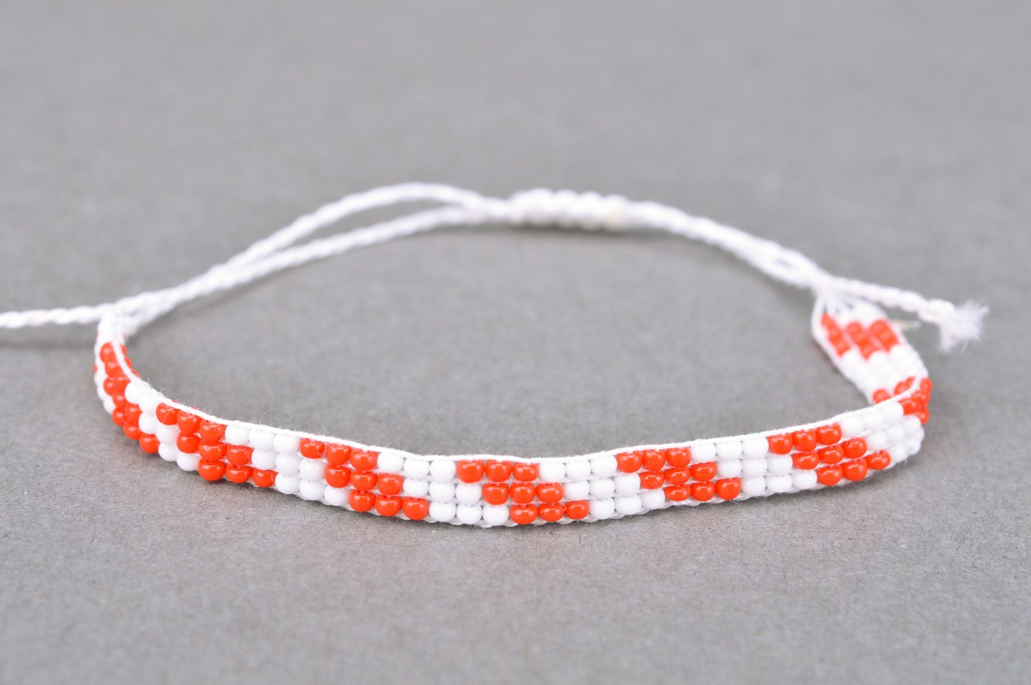 Плетеный браслет на руку из бисера ручной работы красный с белым тонкий фото 2