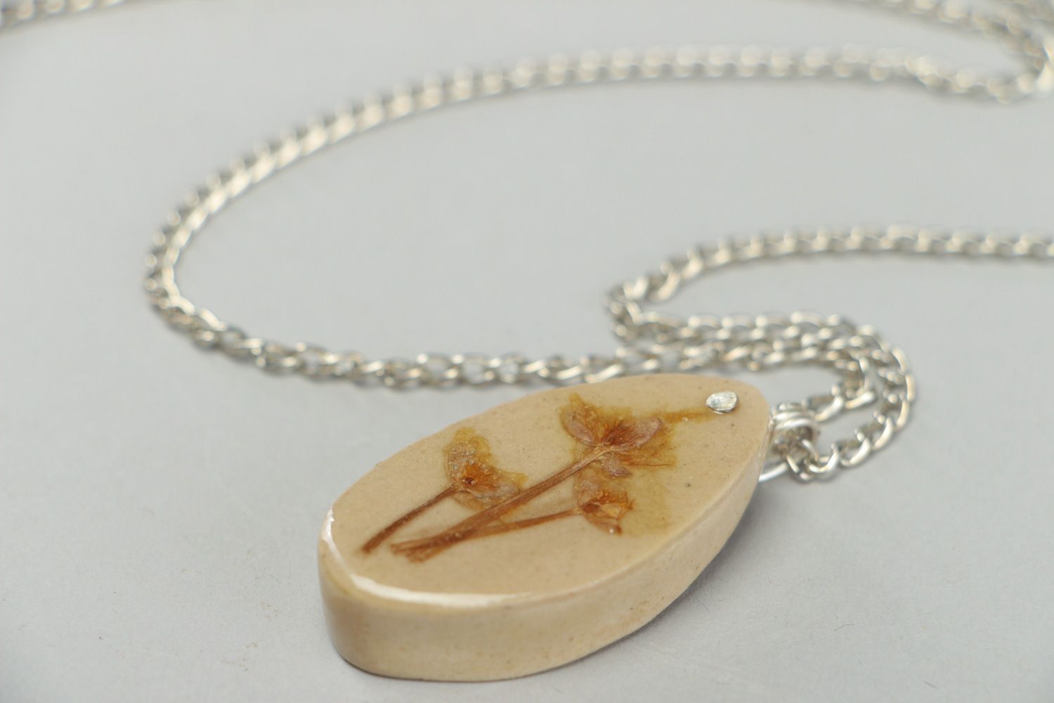 Handmade light oval pendant with flowers embedded in epoxy resin on long chain photo 2