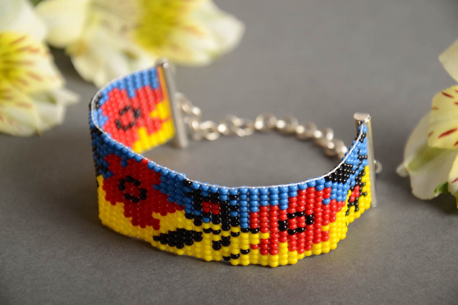 Handmade blue and yellow bead woven wrist bracelet with red poppy pattern