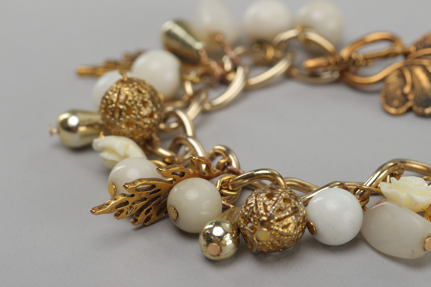 Handmade women's wrist bracelet with charms and beads of white and gold color photo 3