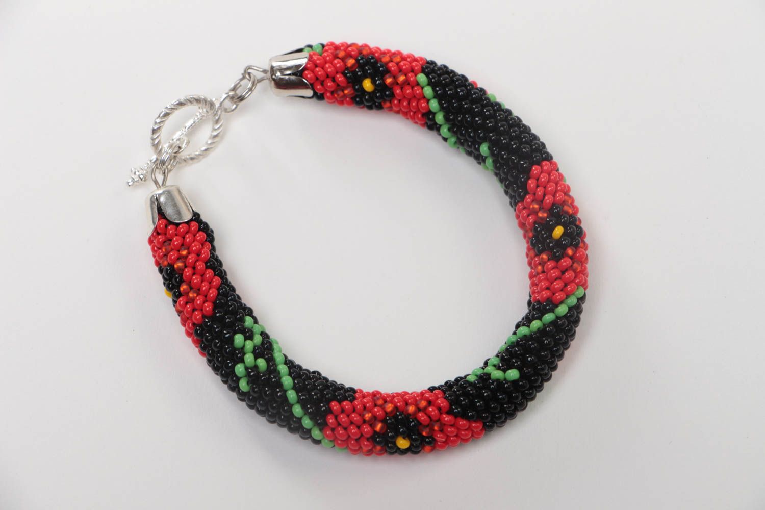 Handmade beaded cord bracelet with red floral pattern on black background photo 2