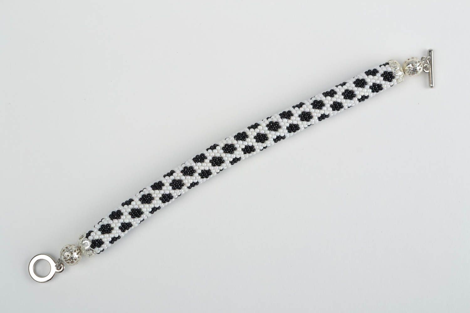 Handgemachtes gehäkeltes schwarz weißes Armband aus Glasperlen in Form von Litze foto 3