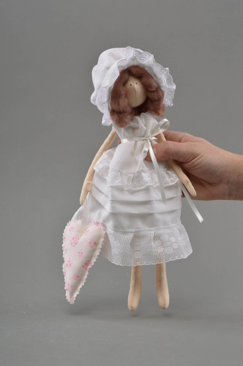 Handmade cute toy doll made of fabric in white dress and bonnet on stand photo 5