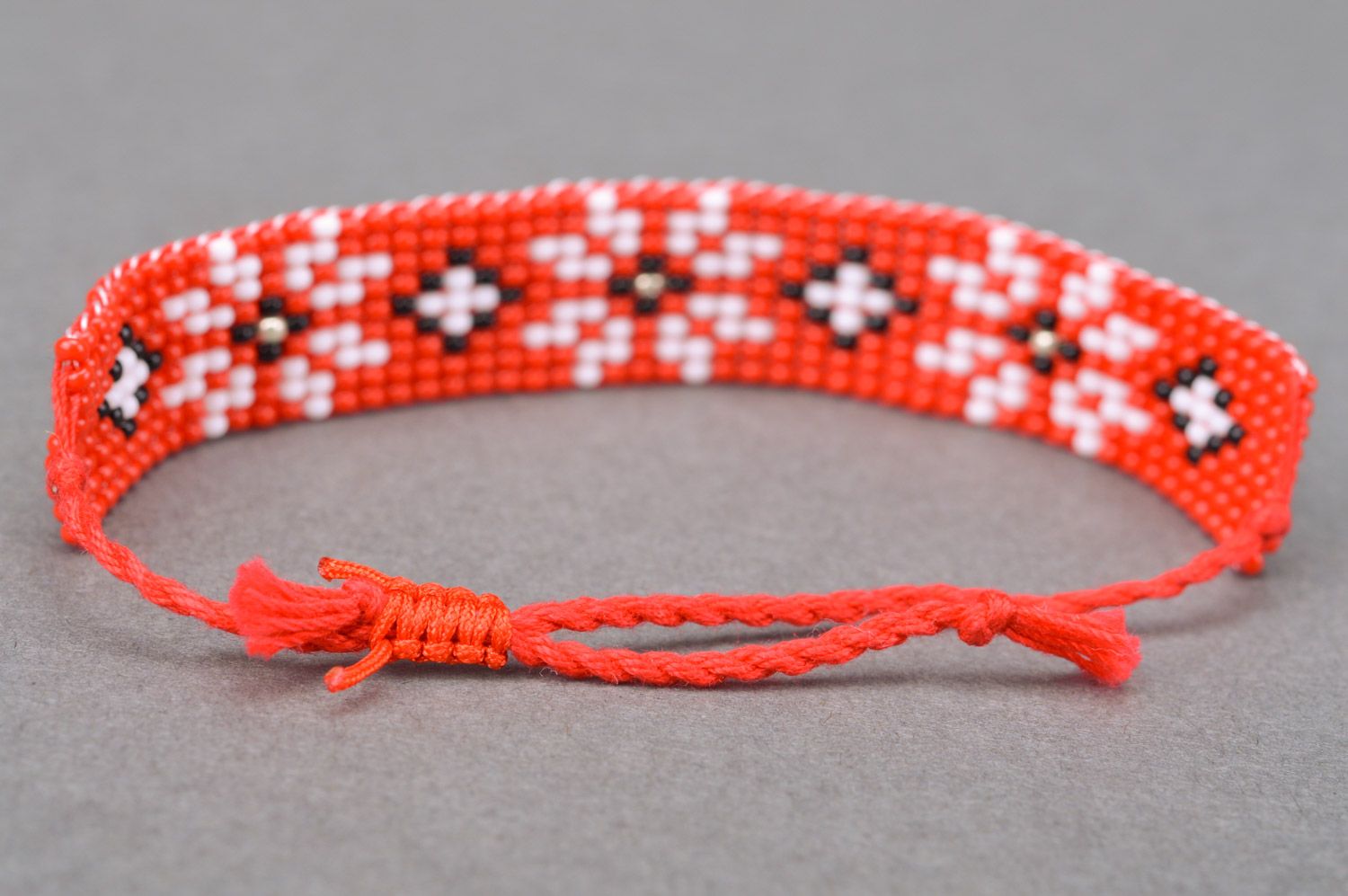 Handmade red beaded wrist bracelet with ties and white flower pattern photo 4