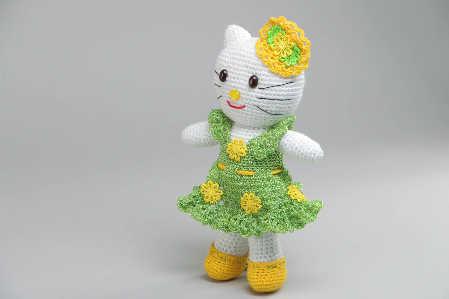 Soft handmade decorative crocheted toy cat in a green dress made of acrylic threads photo 2