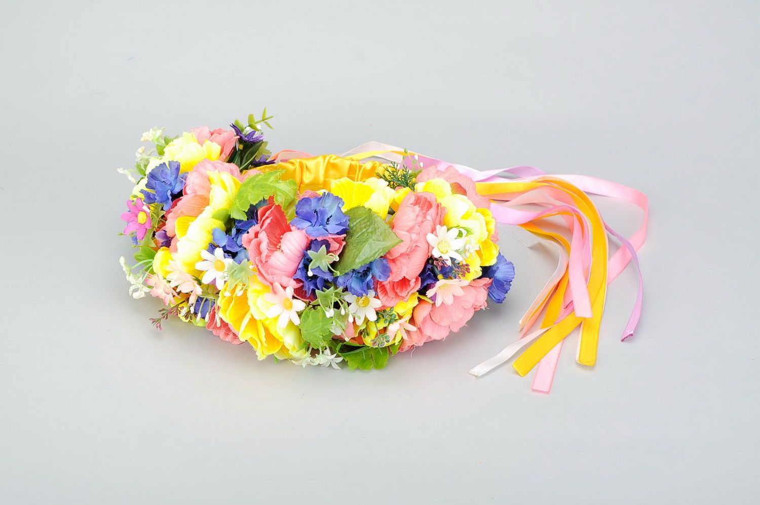 Bright wreath with artificial flowers and ribbons photo 1