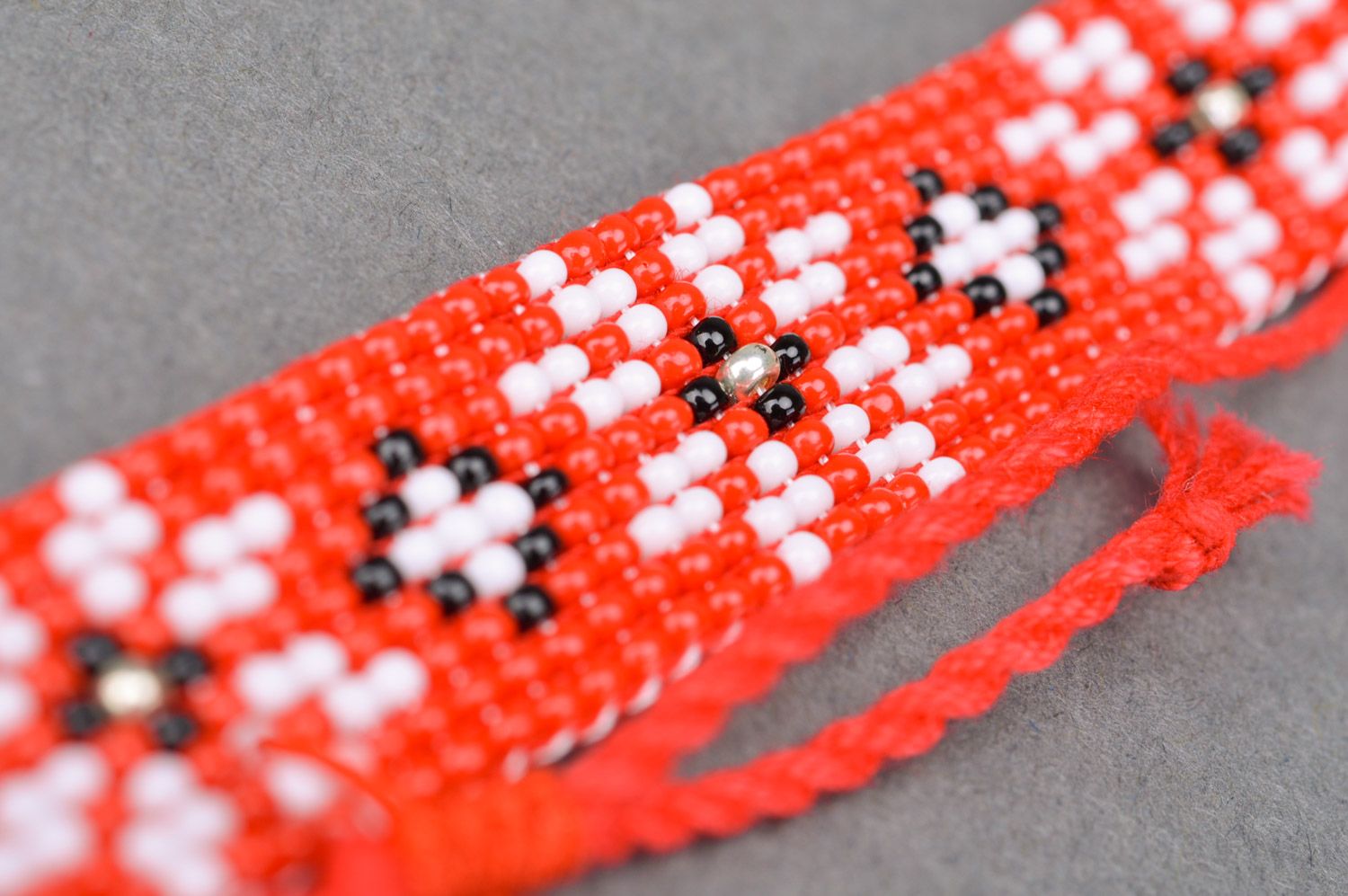 Handmade red beaded wrist bracelet with ties and white flower pattern photo 3