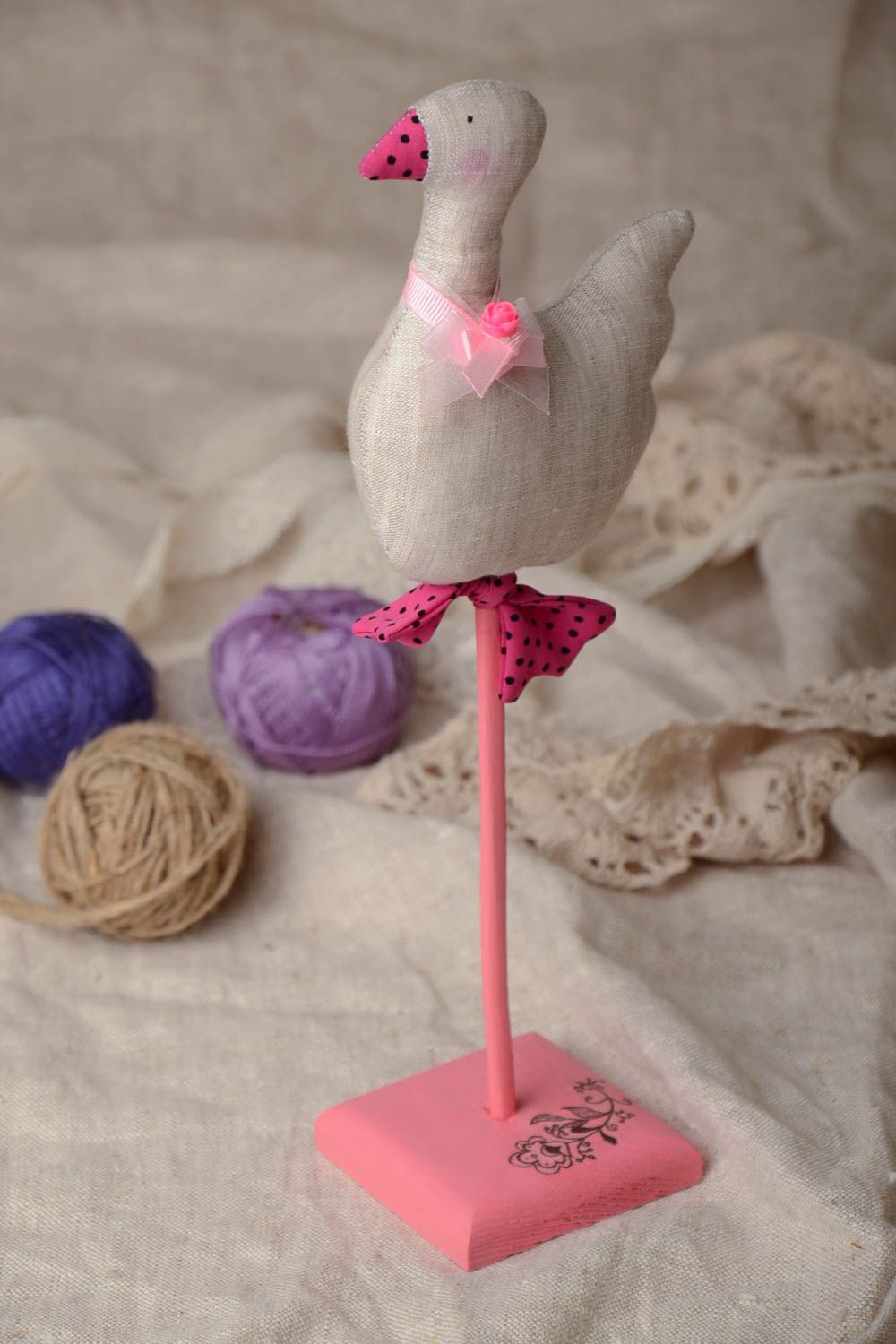 Handgemachte bemalte dekorative Ente aus Stoff mit Schleife und künstlicher Blume auf Ständer foto 1