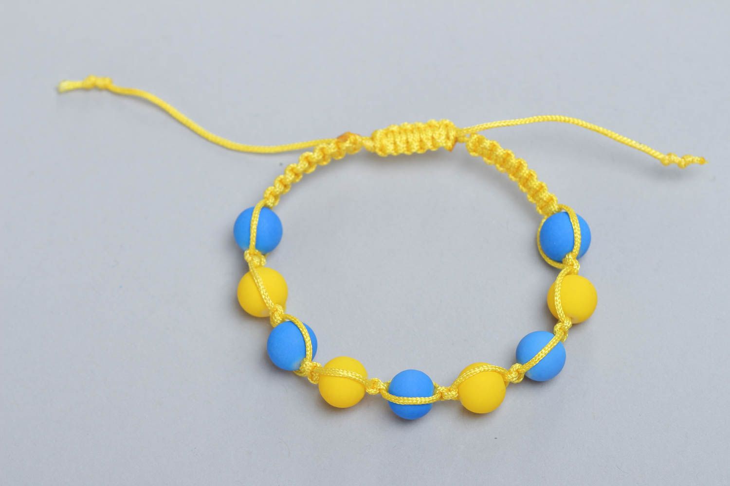 Плетеный браслет из ниток с пластиковыми бусинами ручной работы голубой с желтым фото 3