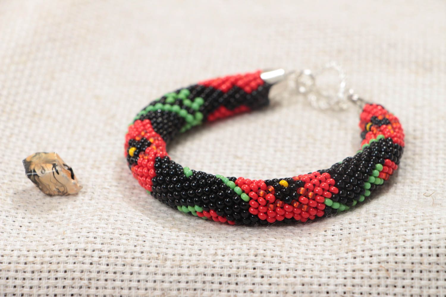 Handmade beaded cord bracelet with red floral pattern on black background photo 1