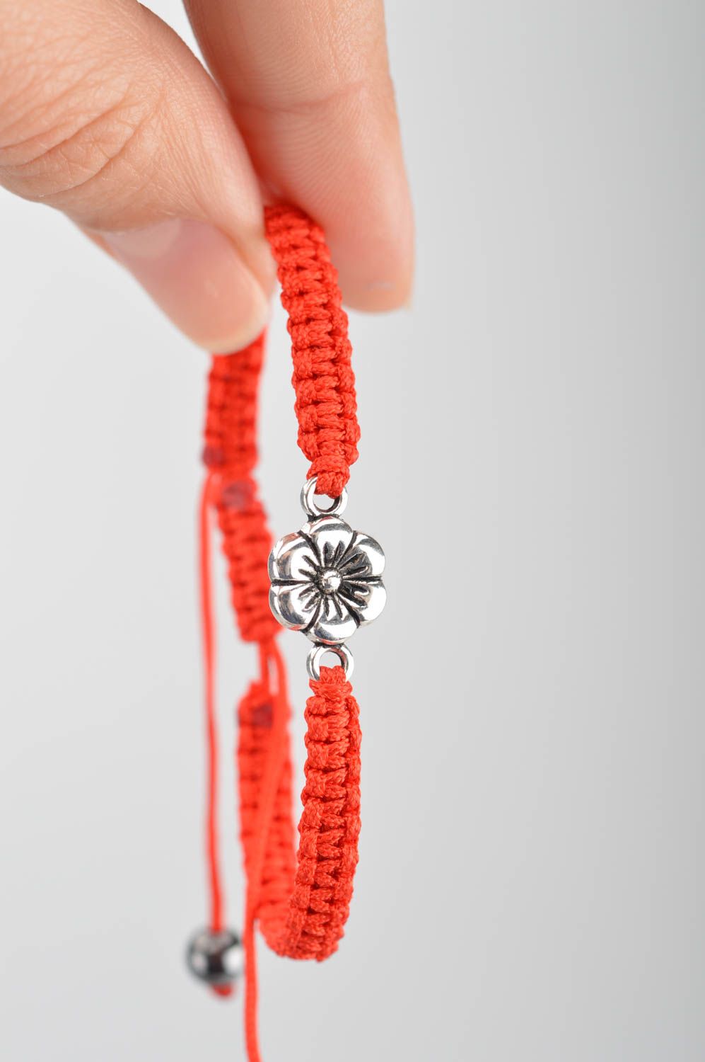 Handmade red bracelet made of silk threads with flower created of metal photo 3