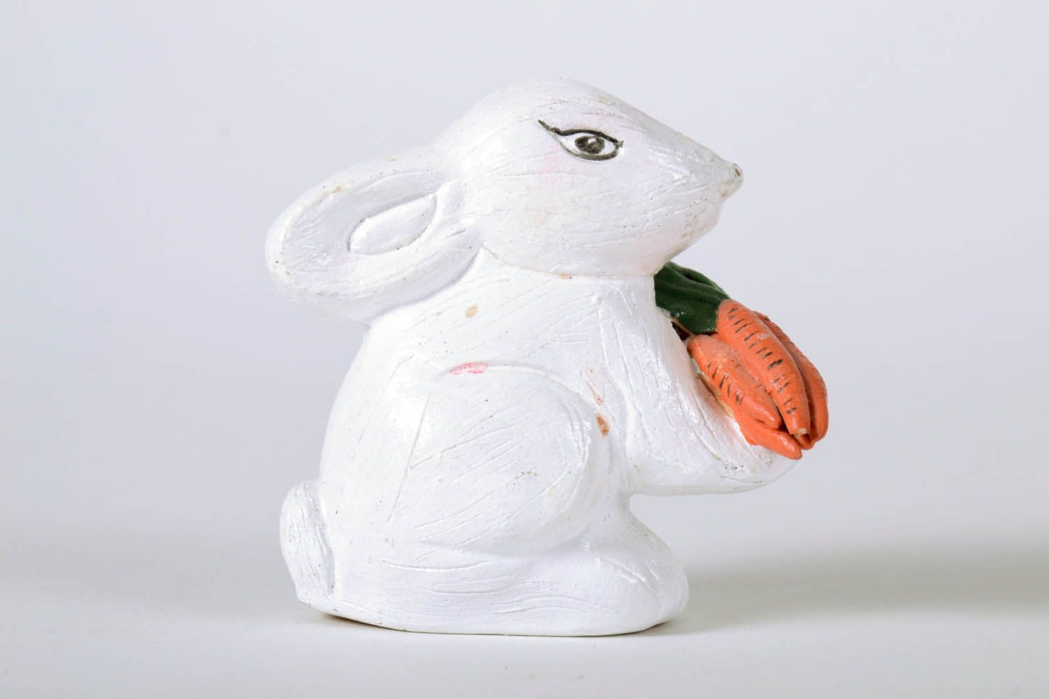 Estatueta de argila feita à mão pintada com tintas acrílicas Coelho de cerâmica com uma cenoura foto 2