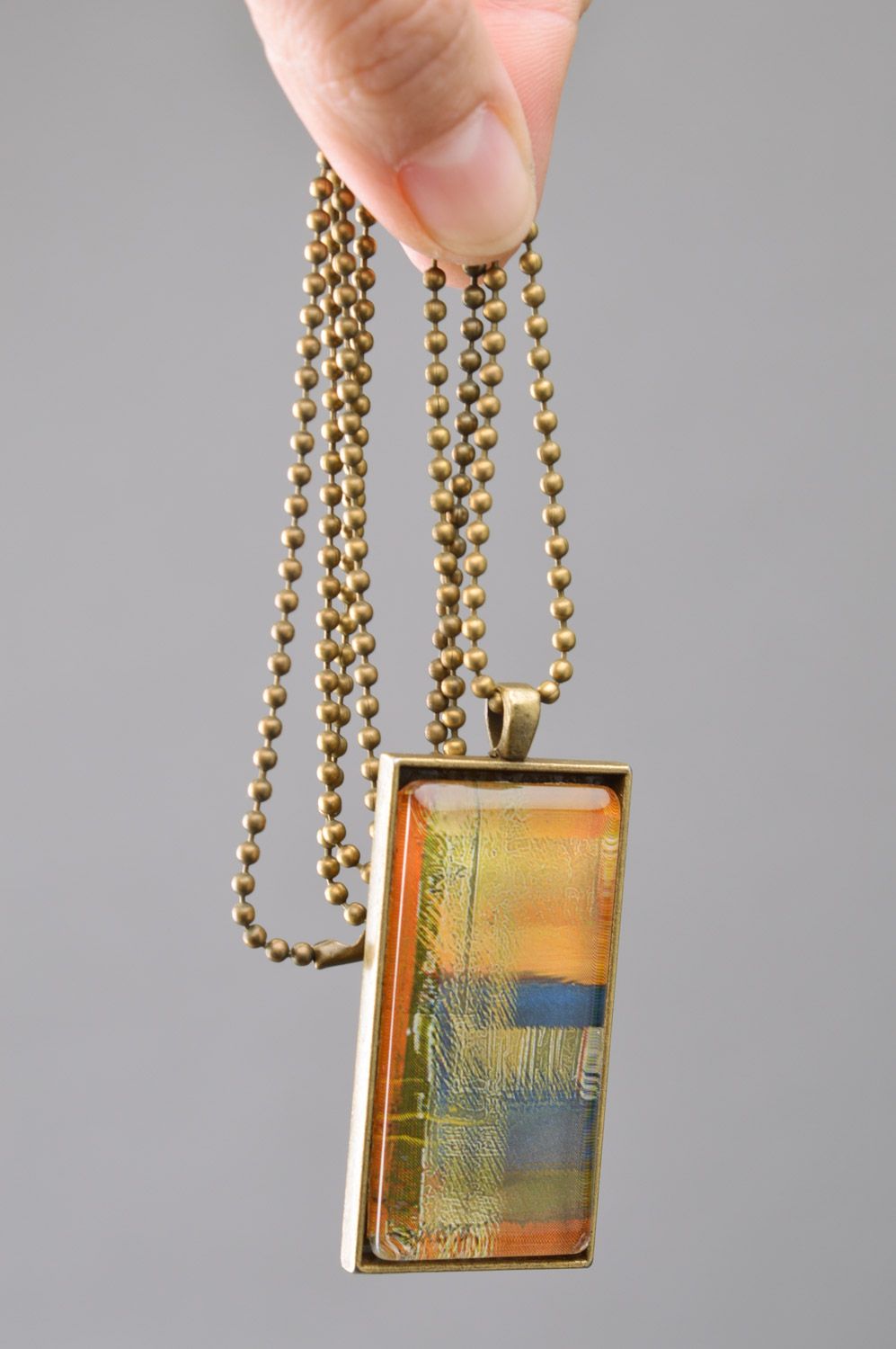 Handmade rectangular metal pendant in warm colors on long chain of bronze color  photo 3