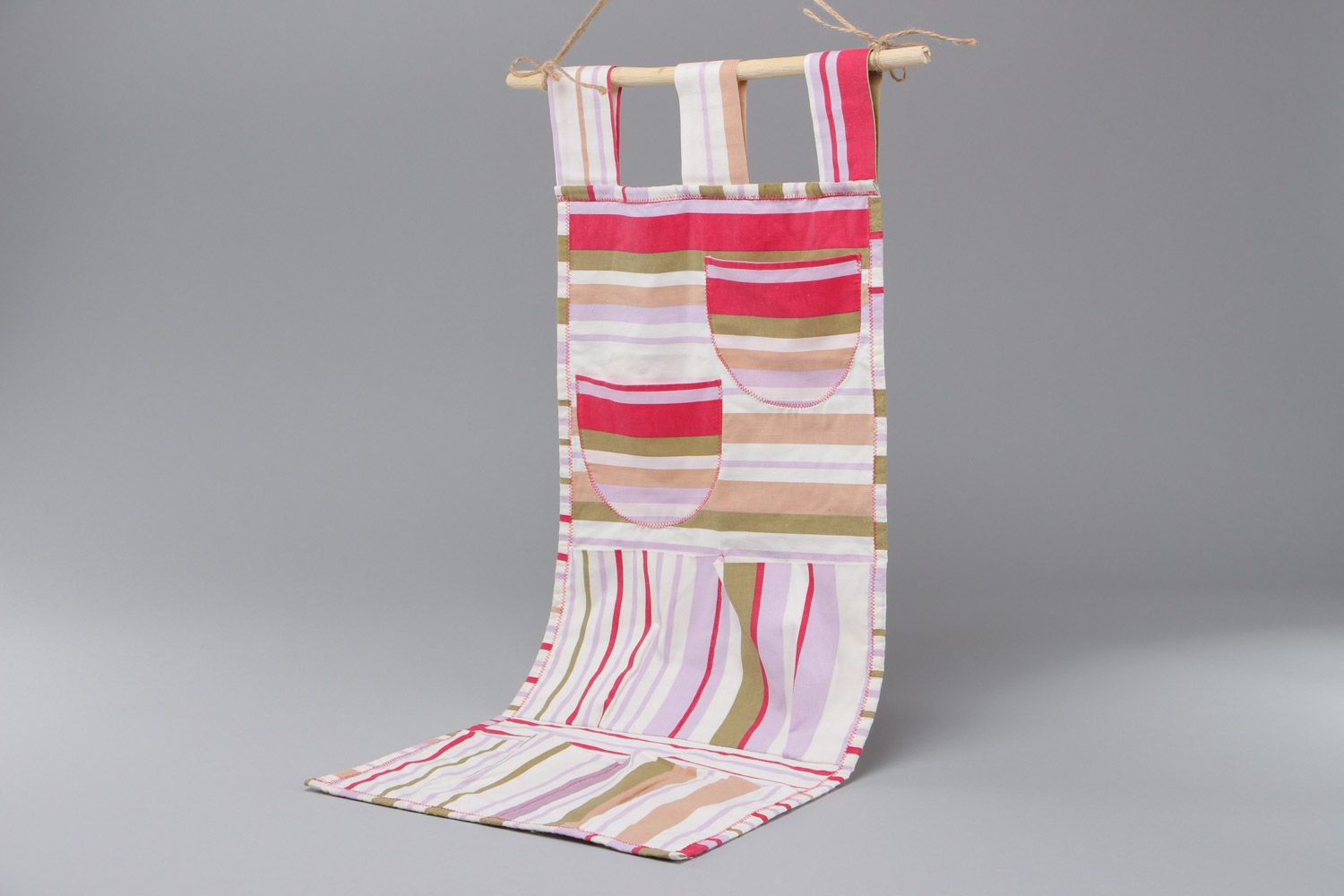 Bright handmade hanging wall pocket organizer sewn of fabric on wooden plank photo 2