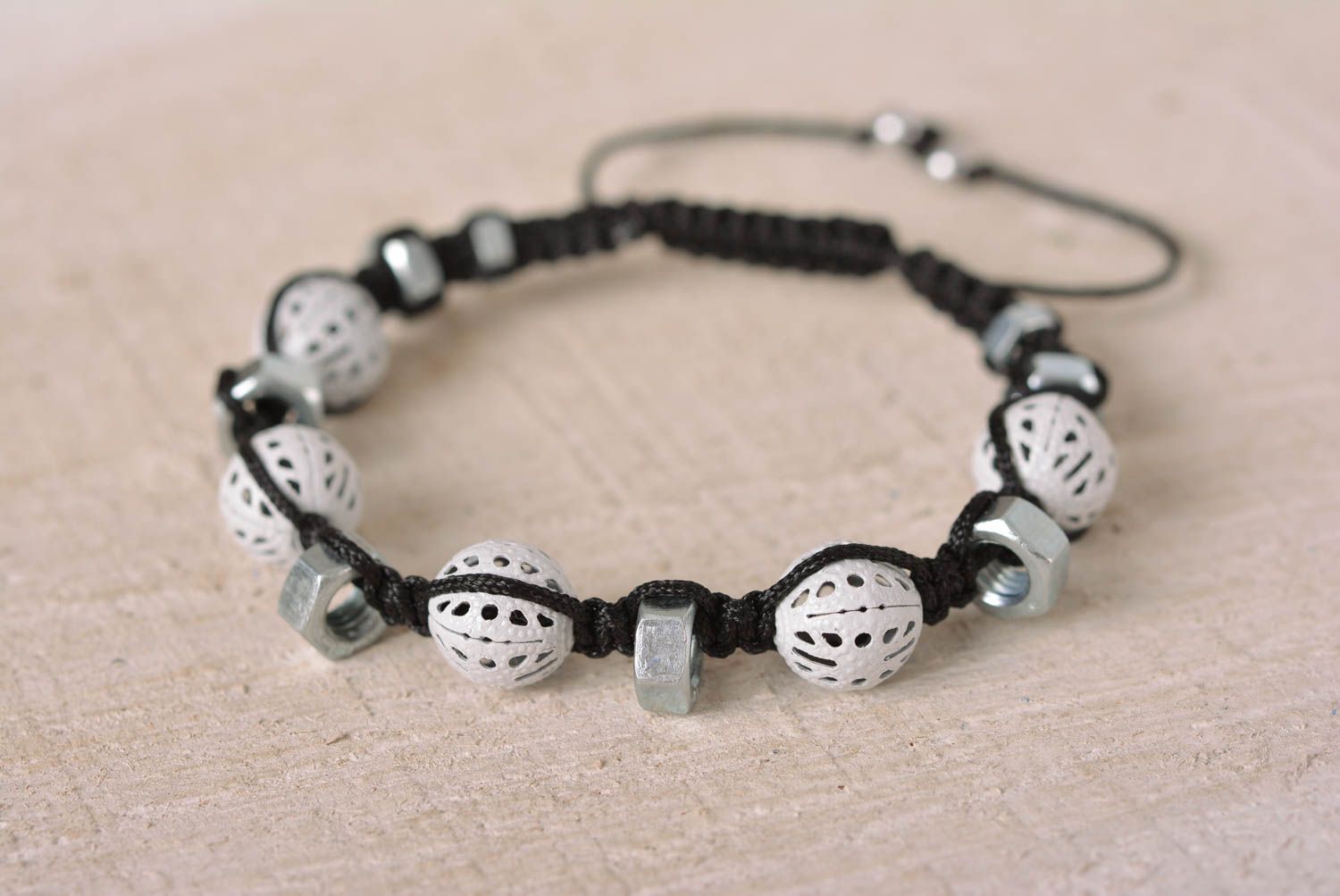 Strand black cord bracelet with white ceramic beads and female metal screws photo 1