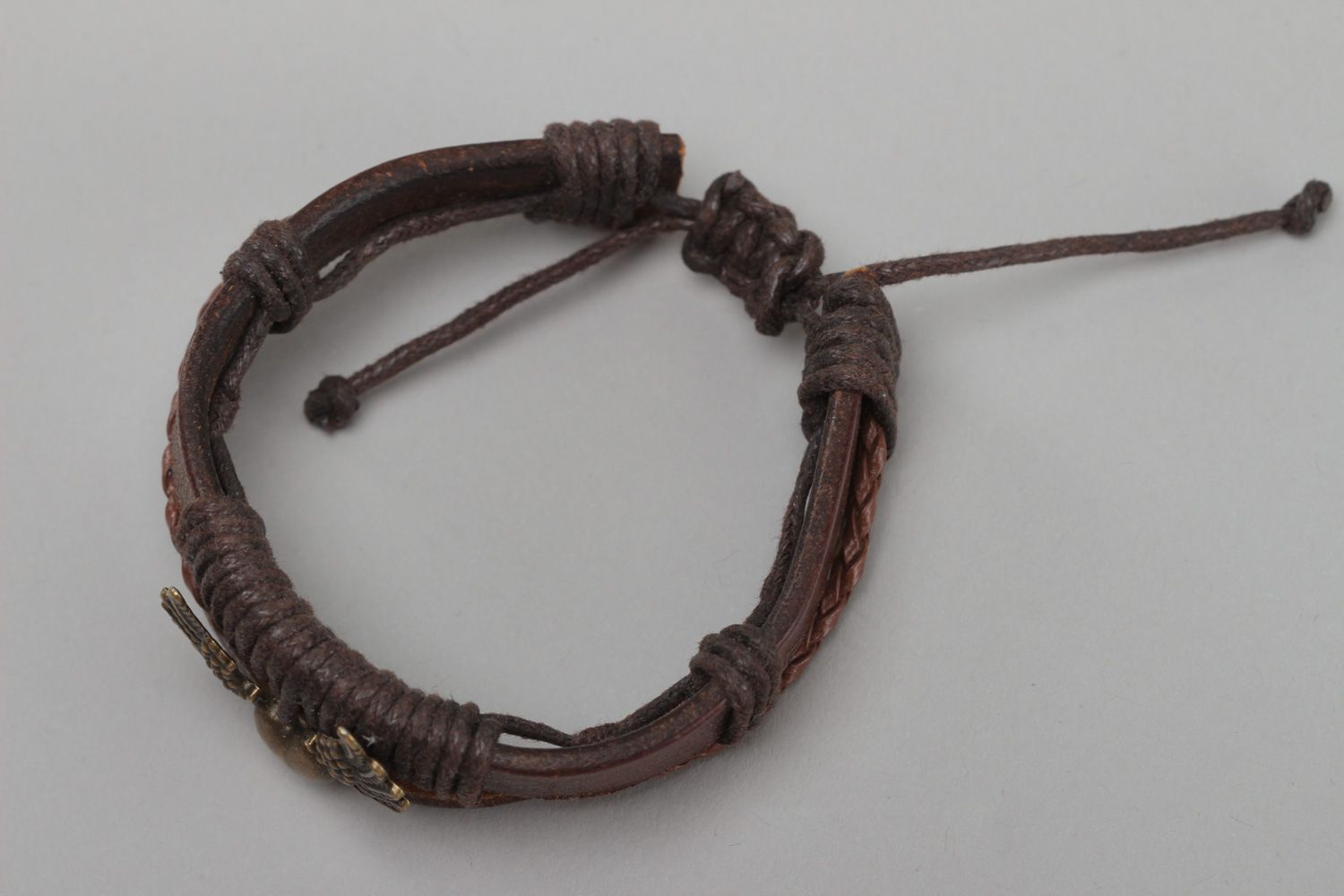 Dark brown handmade wrist bracelet woven of genuine leather with metal wings photo 2