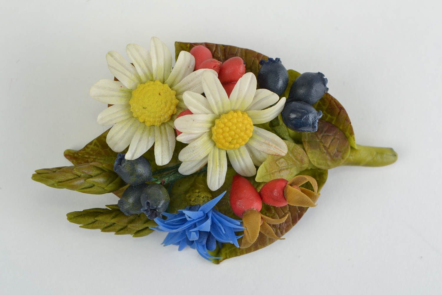Broche artesanal con flores de porcelana fría con manzanillas bayas y acianos  foto 3