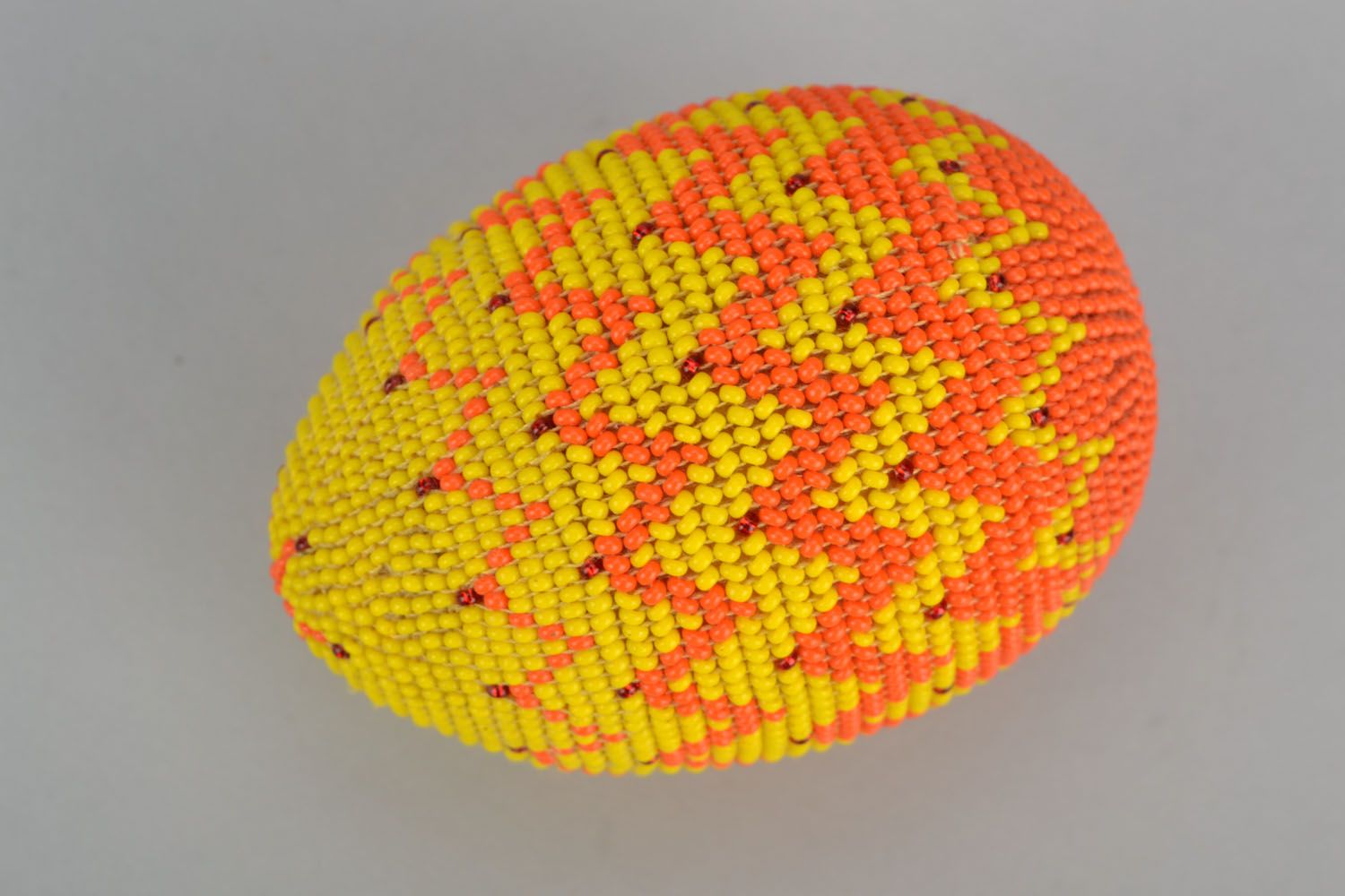 Wooden egg woven over with orange beads photo 1