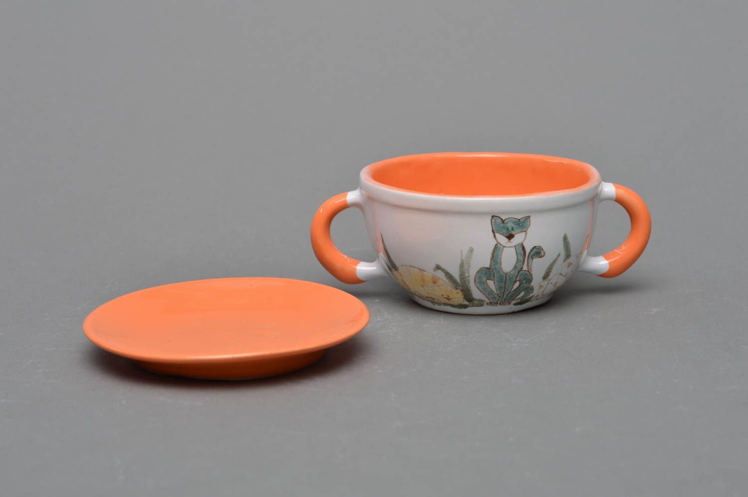 Small kids' ceramic tea cup in white and orange colors with two handles, saucer, and kitty pattern photo 2