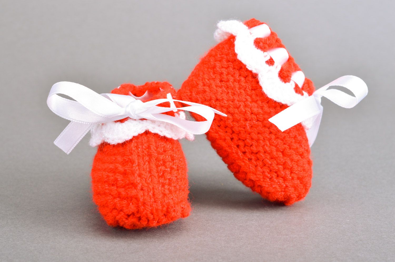 Gestrickte kleine rote Babyschuhe handmade mit Schnürung aus weißen Atlasbändern foto 5
