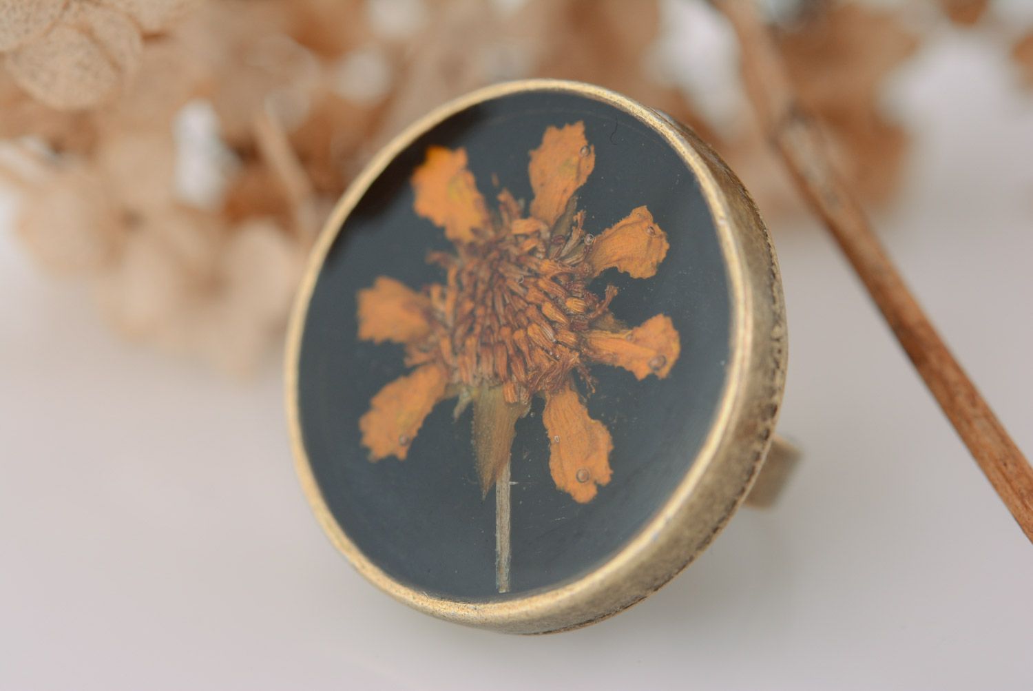 Handmade round metal ring with bright flower on black background in epoxy resin photo 1