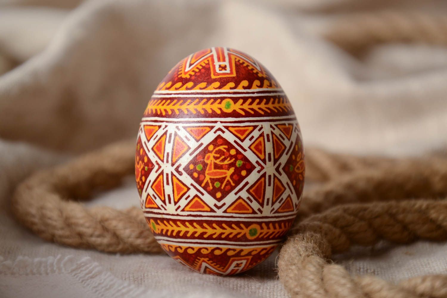 Handmade decorative yellow and red Easter egg painted with wax with deer image photo 1
