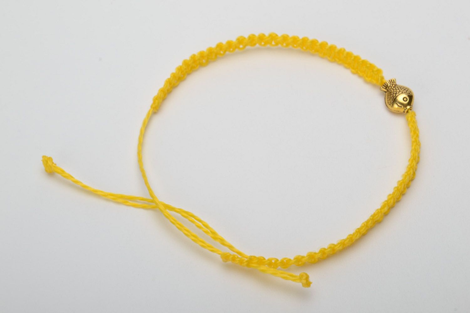 Handmade women's designer macrame woven bracelet of yellow color with metal charm in the shape of fish photo 4