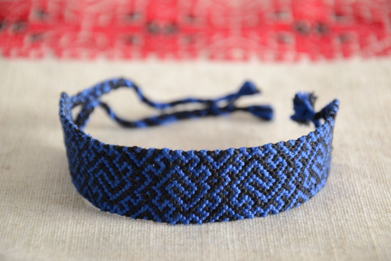 Handmade friendship bracelet woven of threads with blue and black ornament  photo 1