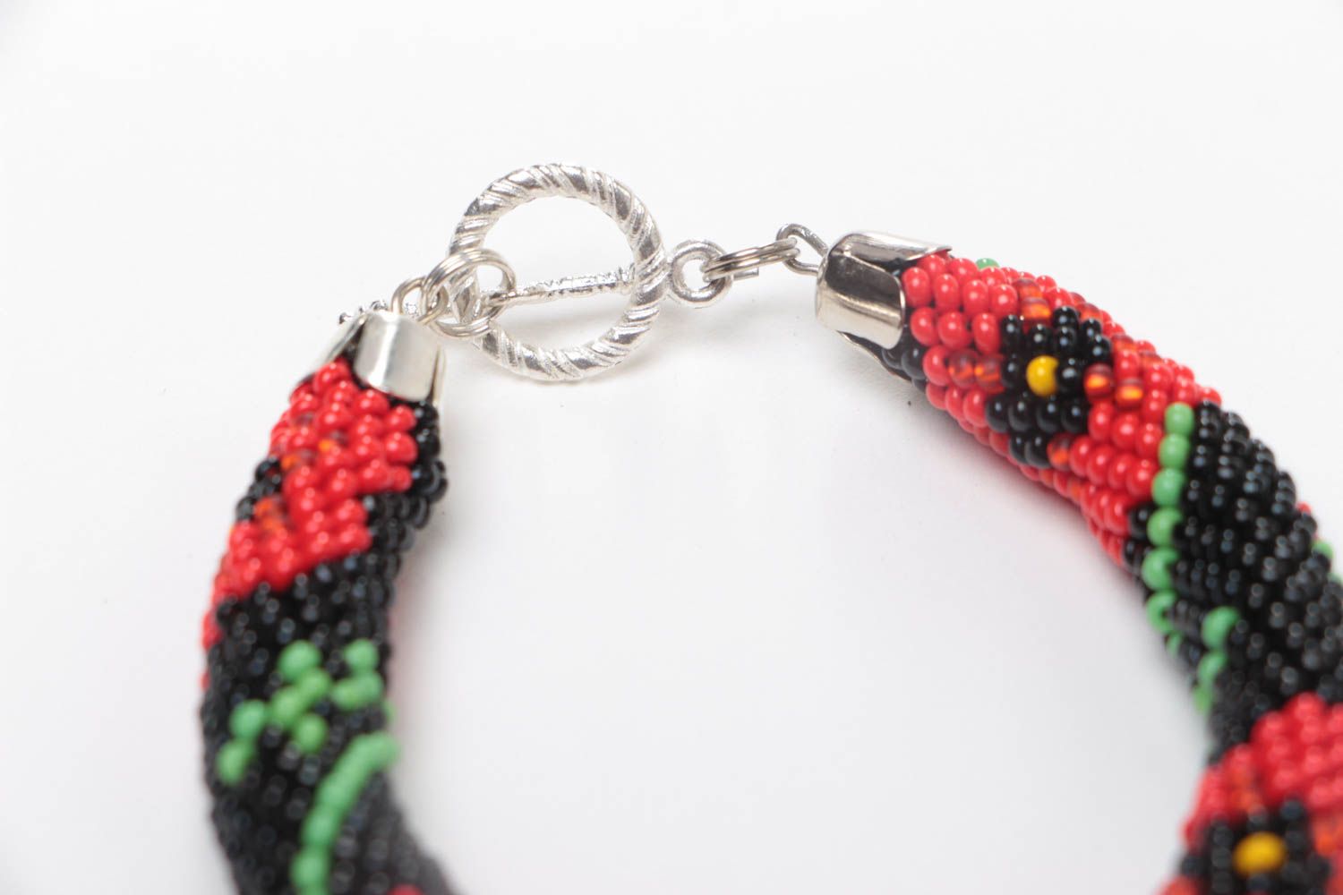 Handmade beaded cord bracelet with red floral pattern on black background photo 4