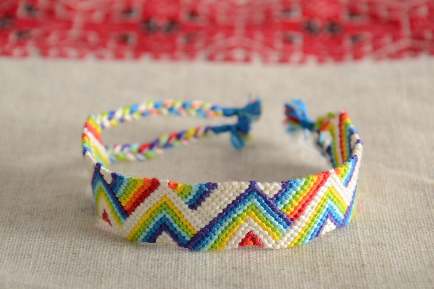 Handmade friendship bracelet woven of threads with rainbow colored ornament photo 1