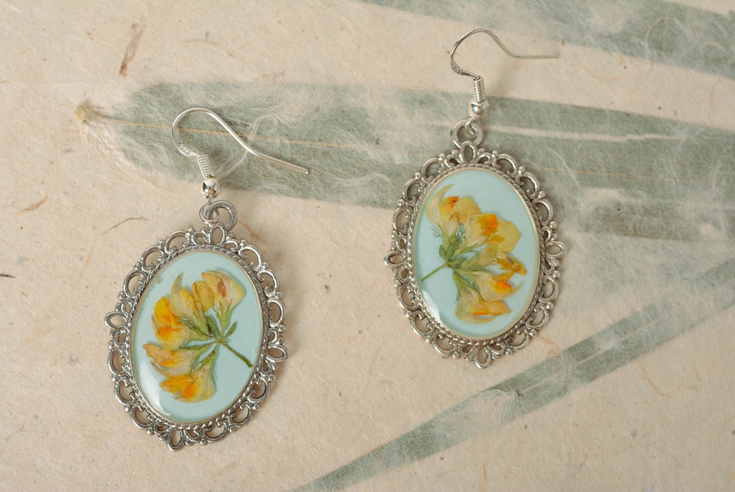 Handmade oval dangle earrings with metal basis and dried flowers in epoxy resin photo 1
