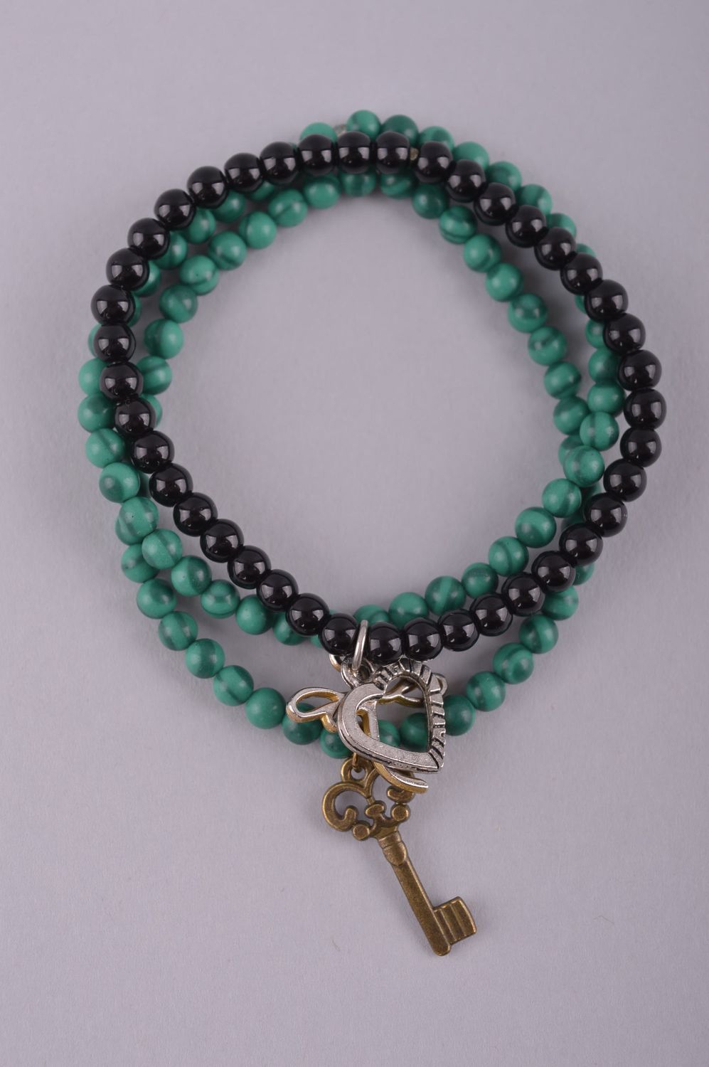 Handmade beaded set of the three-row bracelet on elastic cord with black, dark green beads and charms in butterfly heat and door key shape photo 2