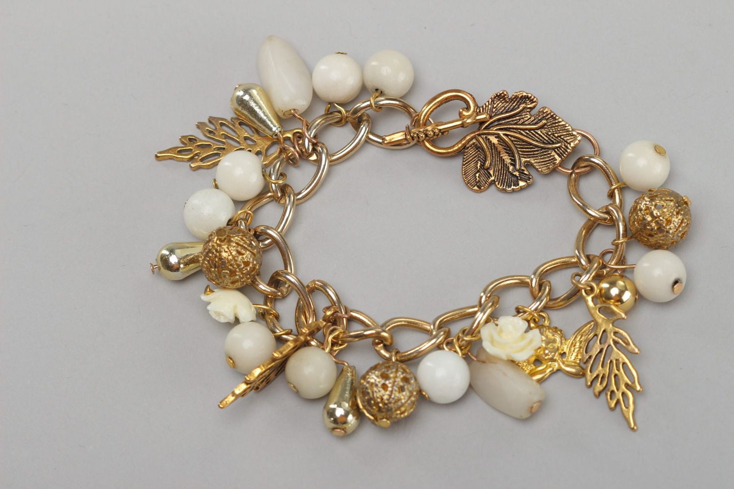 Handmade women's wrist bracelet with charms and beads of white and gold color photo 2