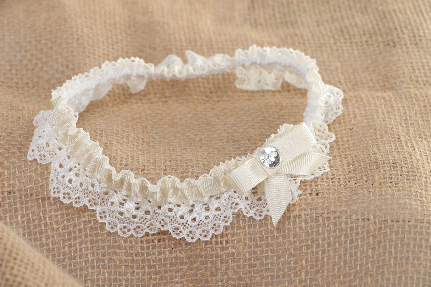 Handgemachtes weißes Strumpfband für Hochzeit aus Spitze und Ripsbändern mit Glasperle foto 1