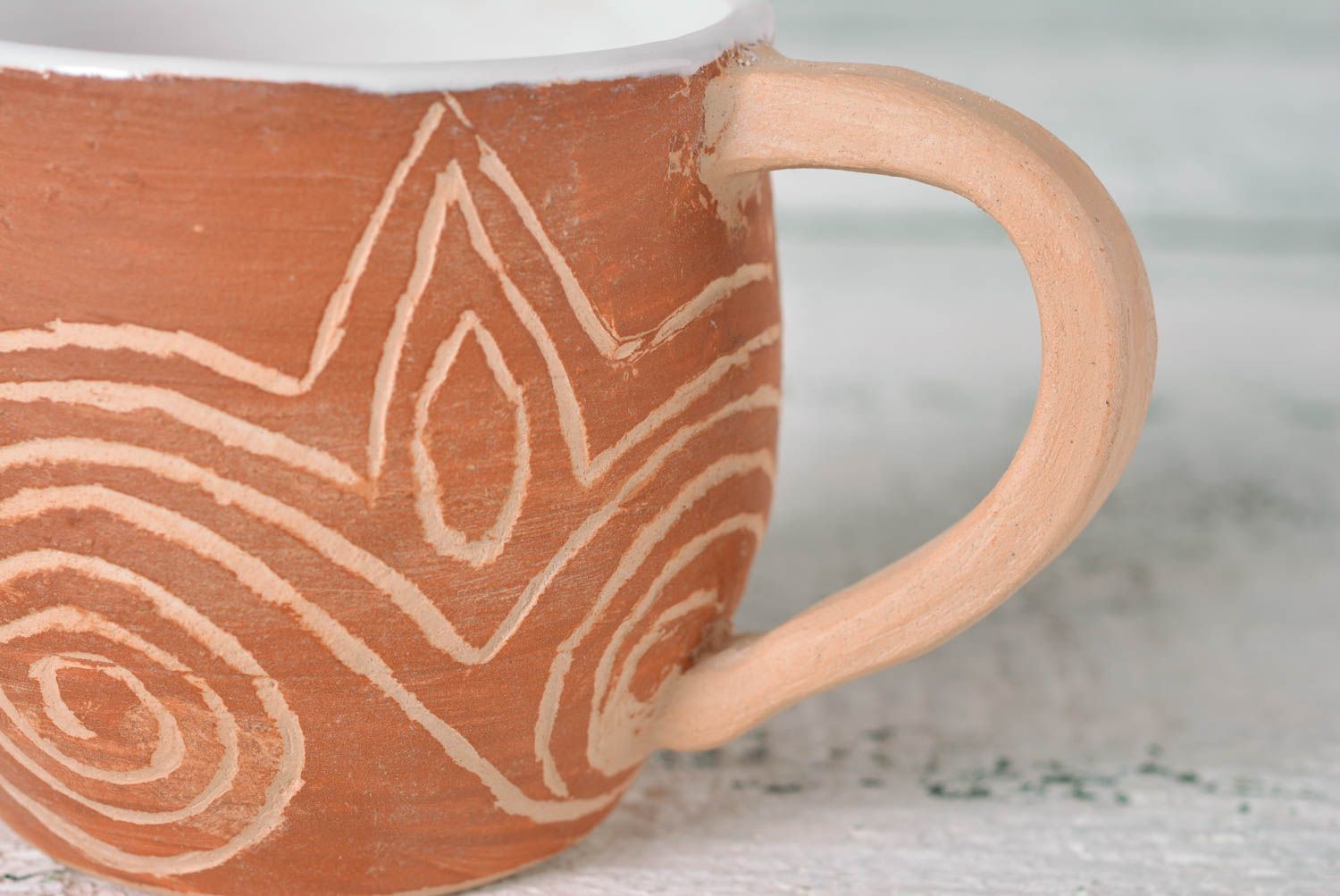 Rustic clay cup in white and brown color with handle and cave drawings photo 3