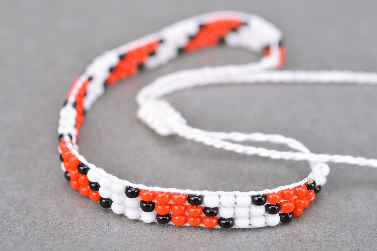 Handmade thin beaded bracelet with red and black pattern and ties photo 4