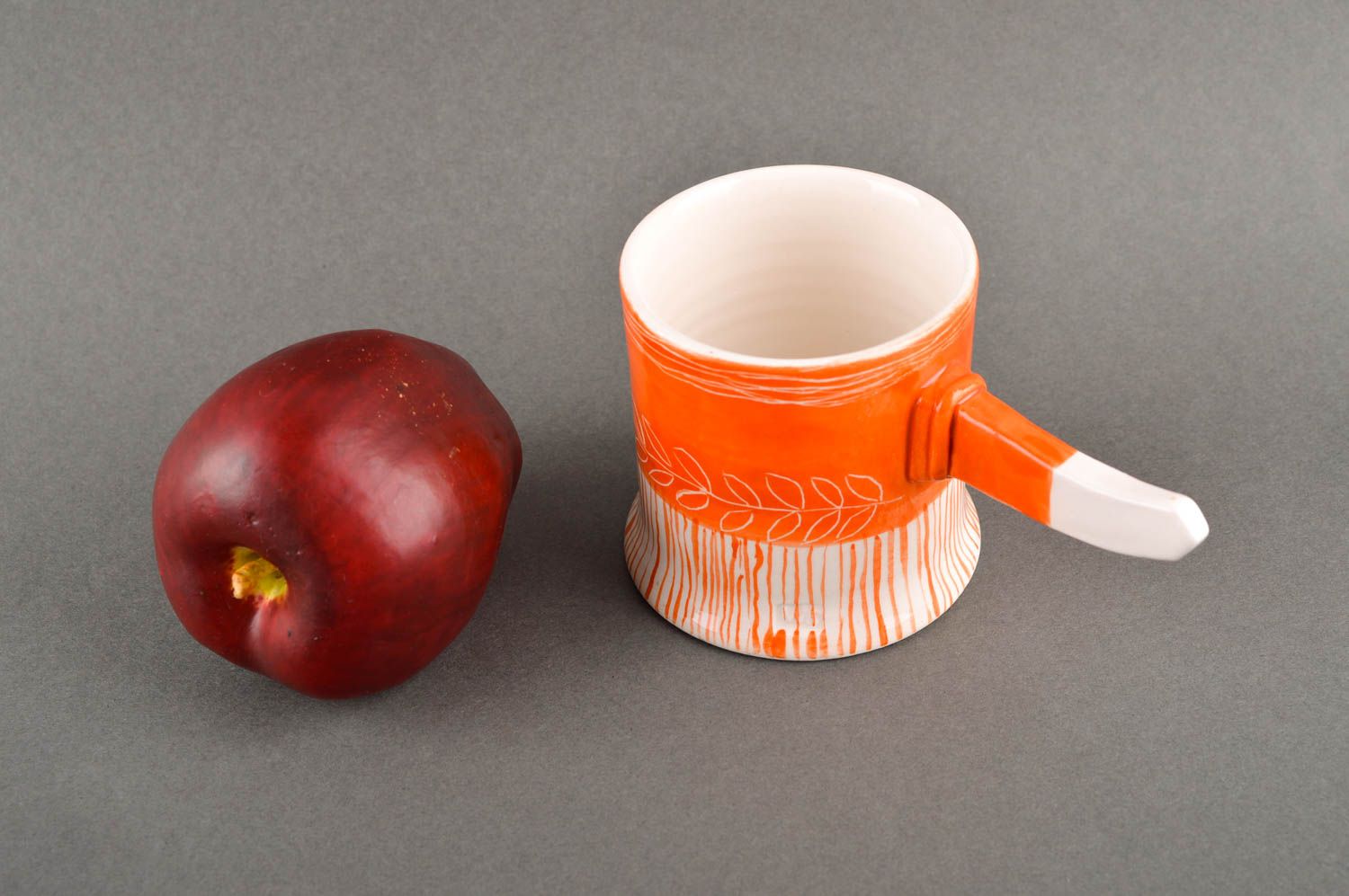 Art style porcelain drinking cup in orange and white color. Stick shape handle. photo 1