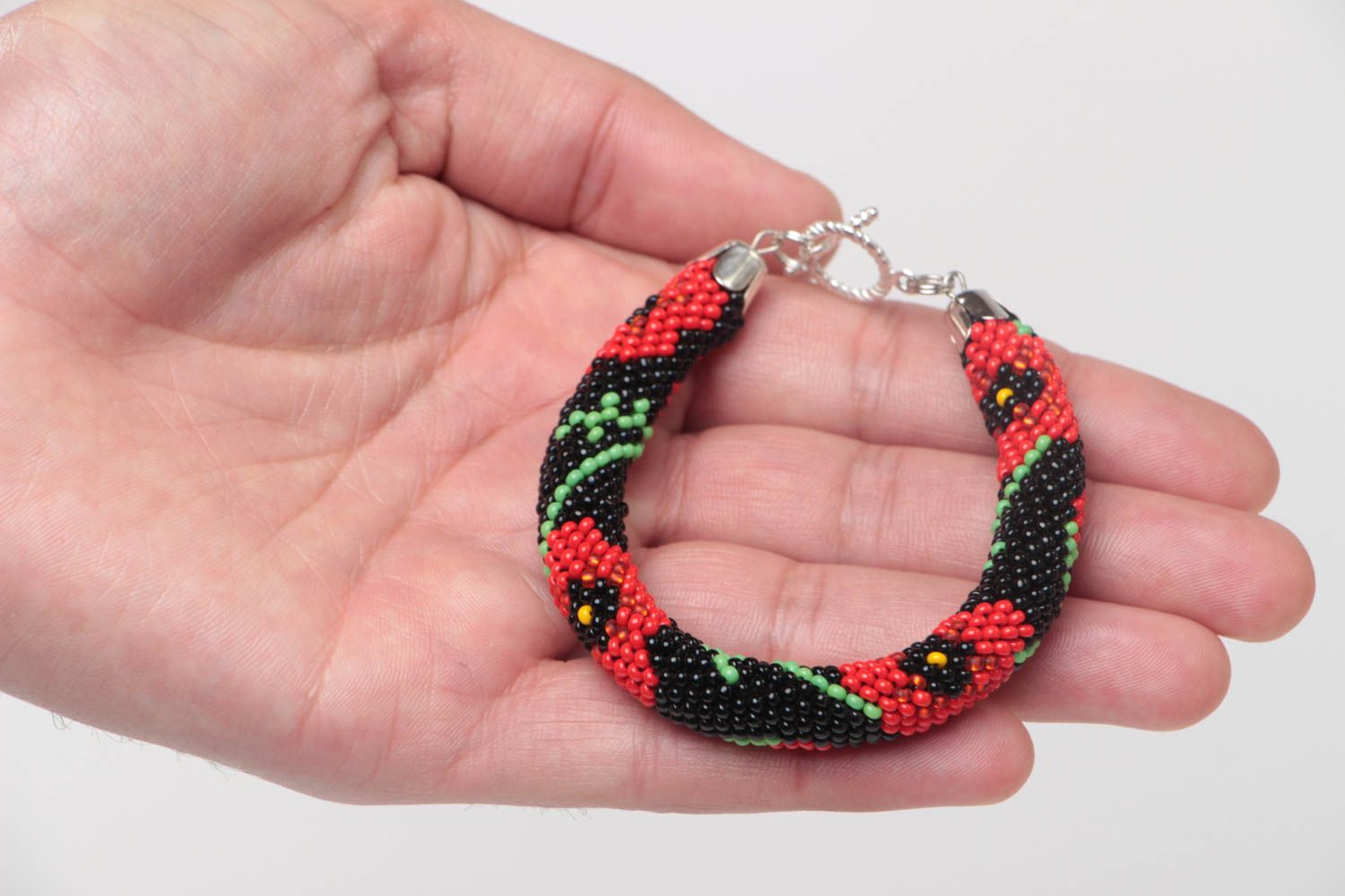 Handmade beaded cord bracelet with red floral pattern on black background photo 5