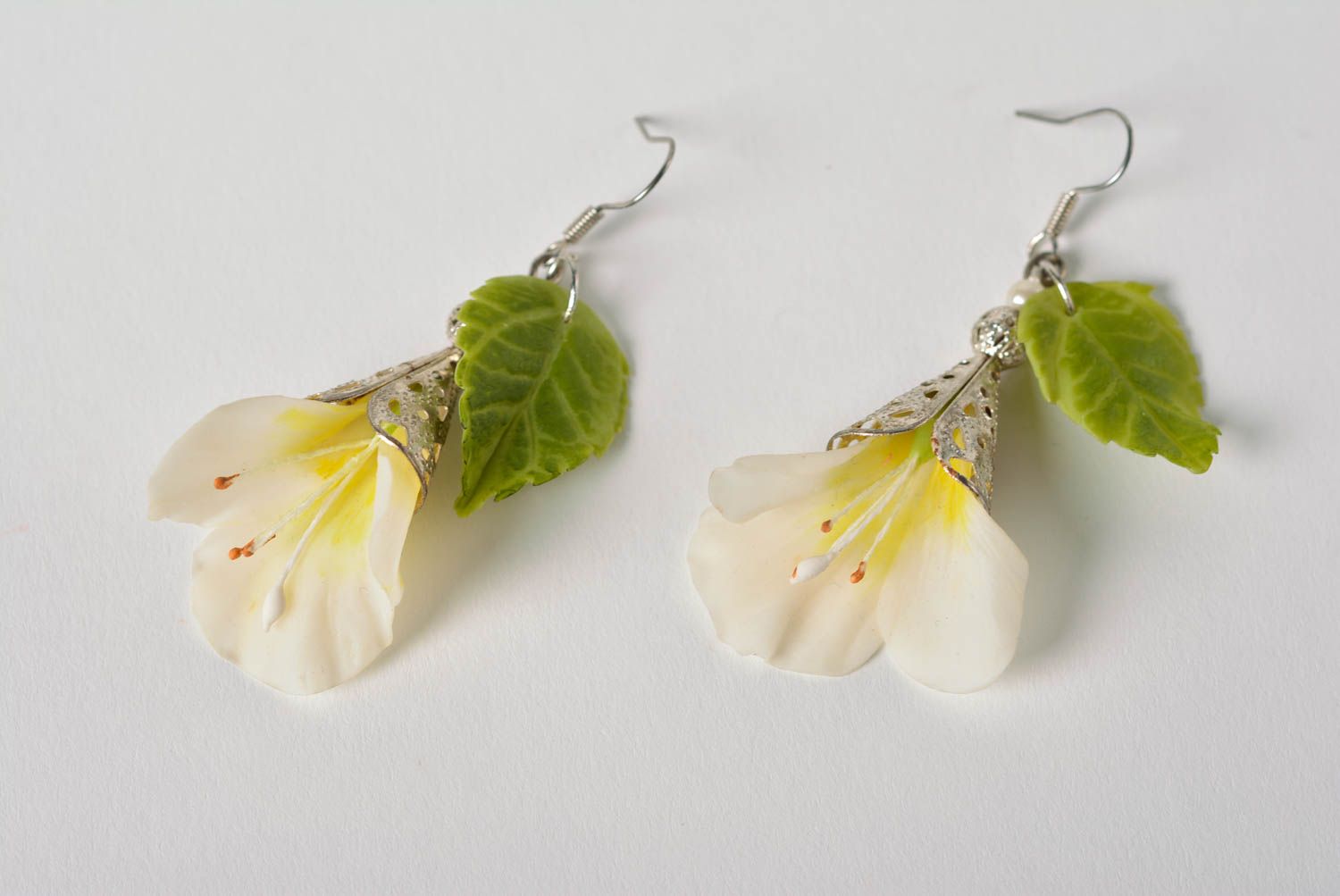 Handmade long earrings with white flowers and green leaves on metal basis photo 2