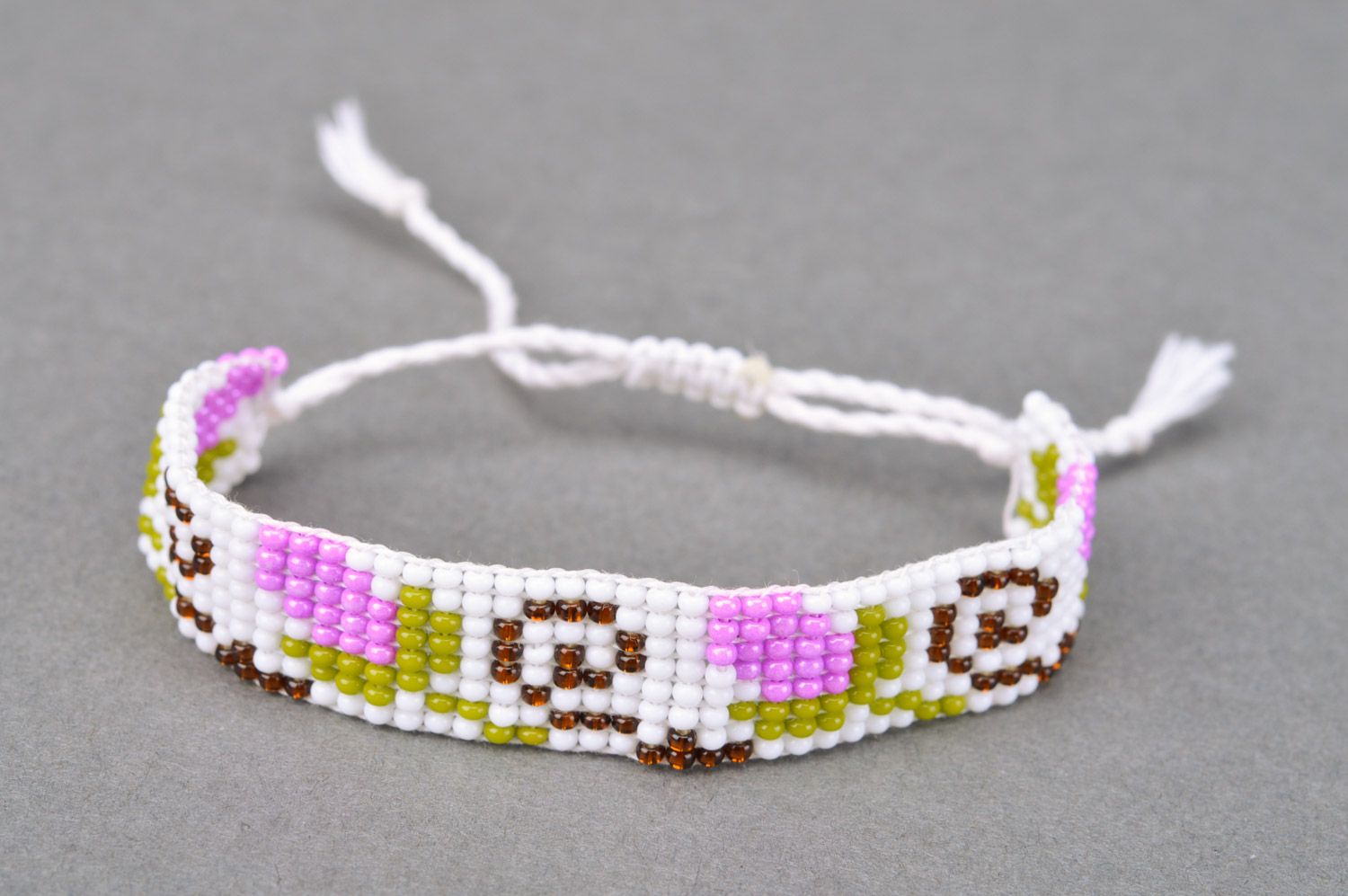 Stylish handmade women's wrist bracelet woven of beads and threads of light color with flower pattern photo 2
