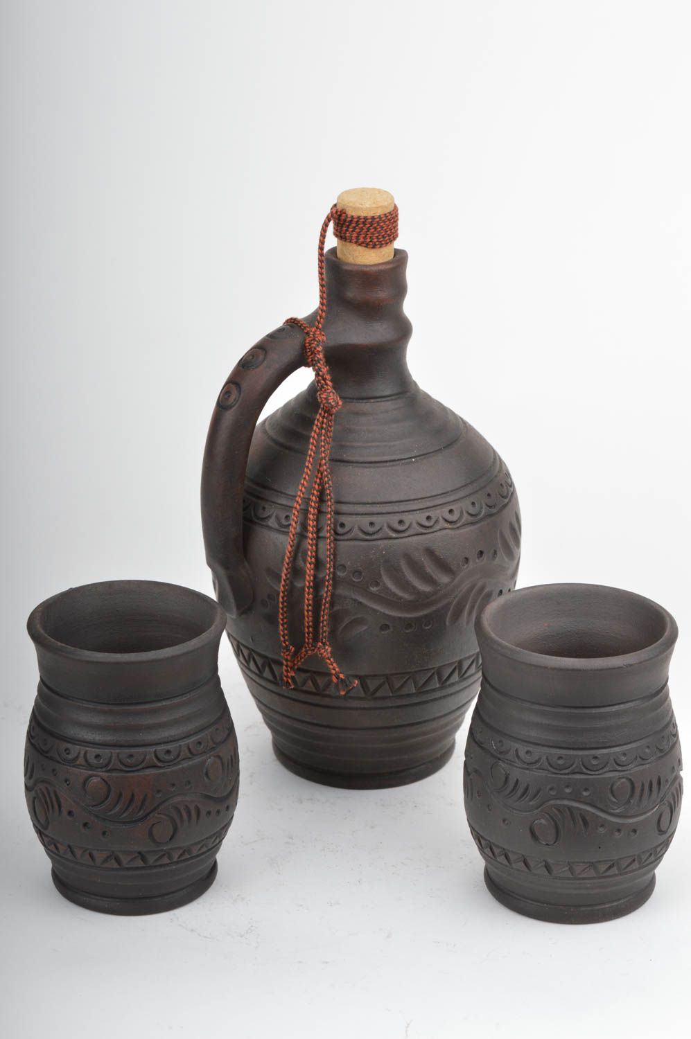 Set of dark brown ceramic drinkware pottery of wine bottle and two wine cups with rustic pattern photo 2