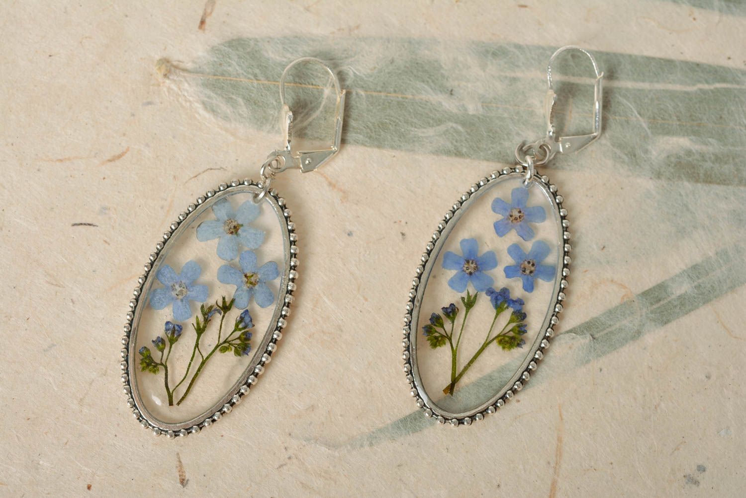 Handmade oval transparent dangle earrings with blue dried flowers in epoxy resin photo 1