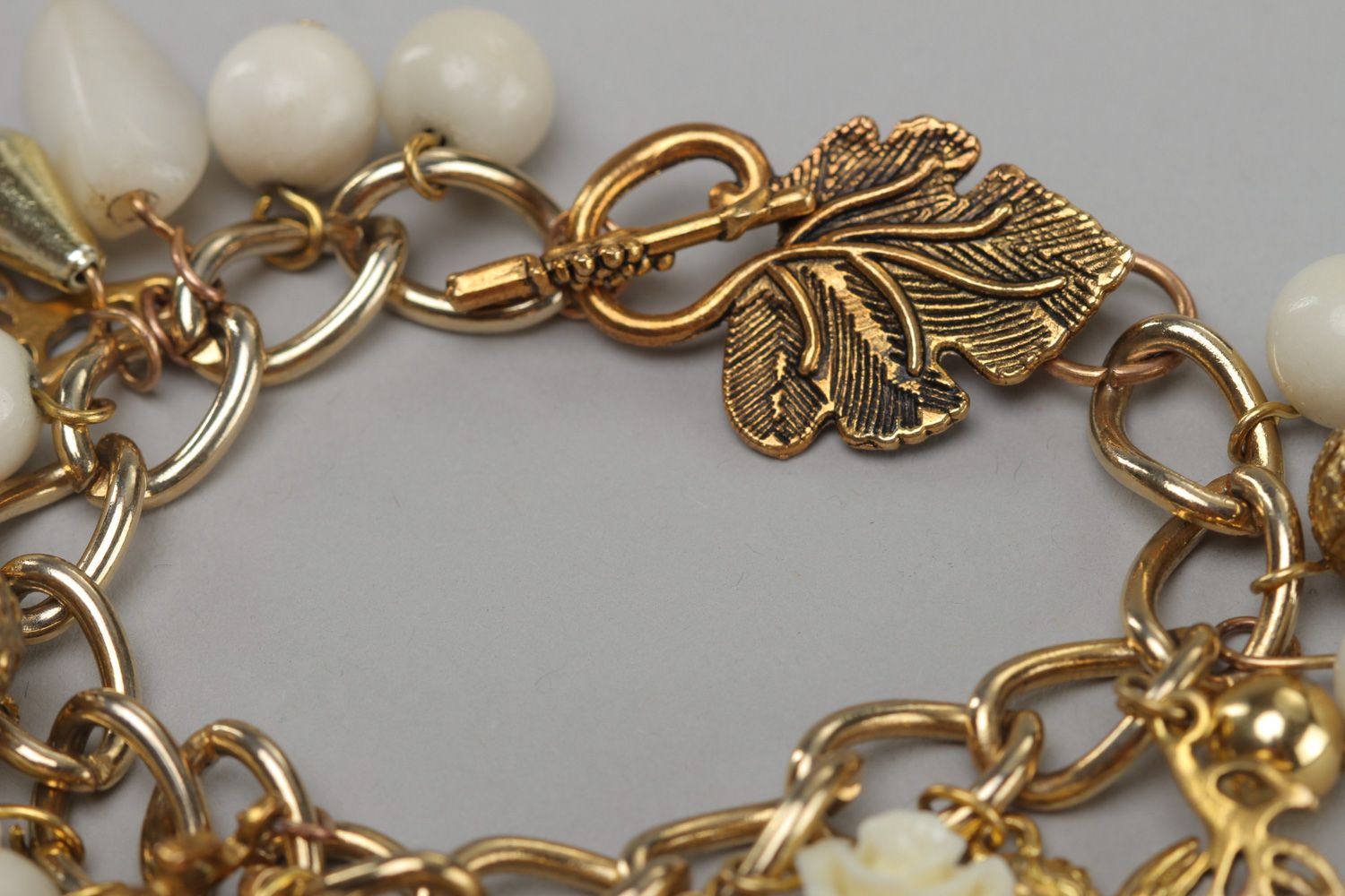 Handmade women's wrist bracelet with charms and beads of white and gold color photo 4