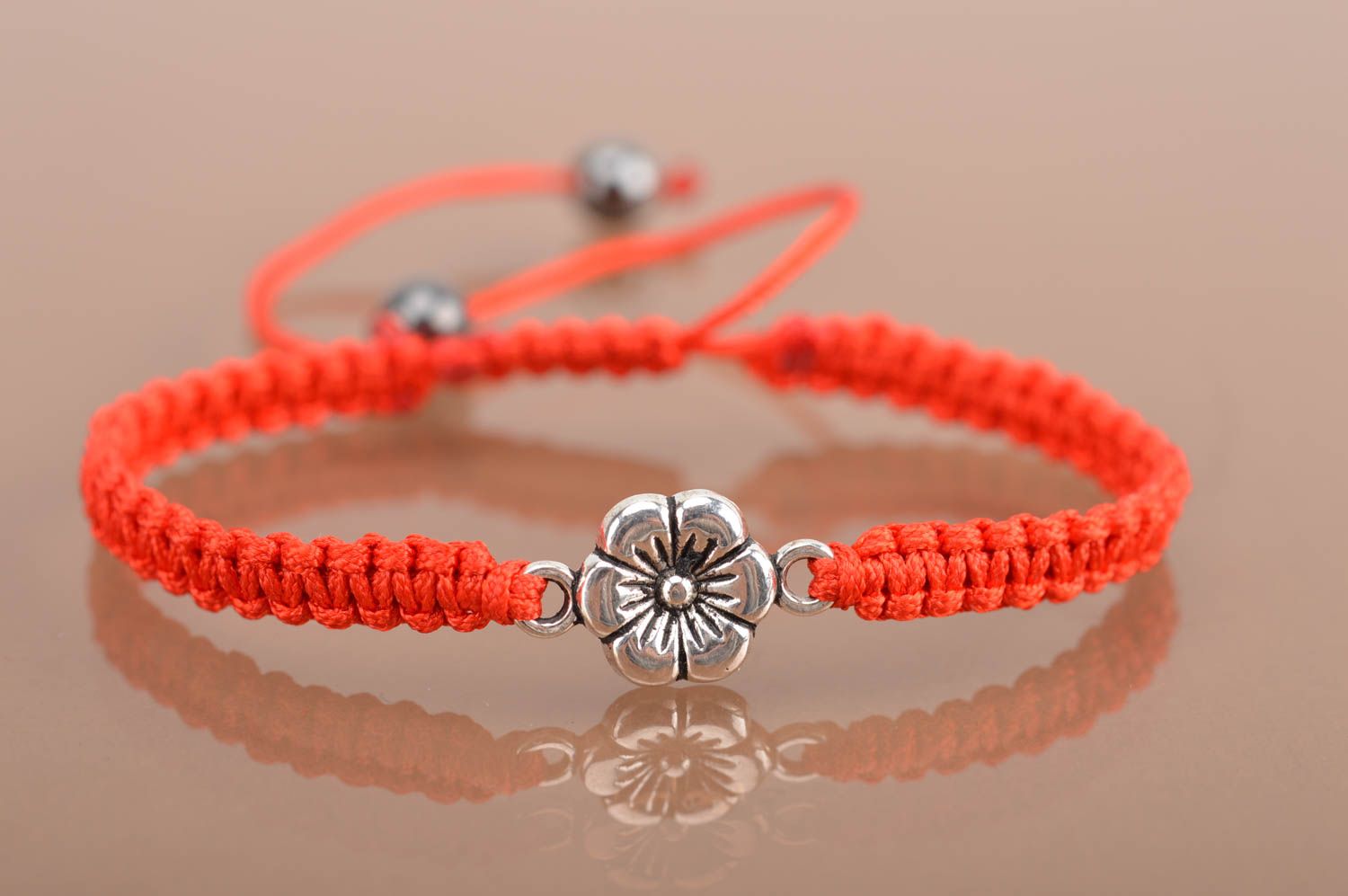 Handmade red bracelet made of silk threads with flower created of metal photo 2